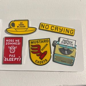 5 enamel pins from the movie the French Dispatch. No crying typewriter mustard